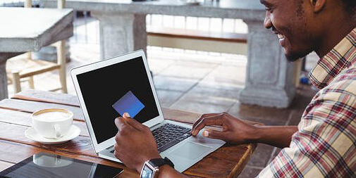 Man doing online shopping with credit card on laptop in cafeteria 600x300